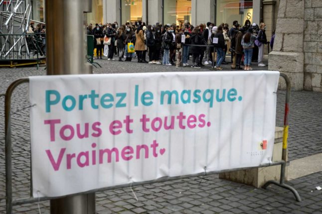 A queue of people in Geneva on the last shopping day before Switzerland went back into lockdown in January 2021. The sign, in French, says “Wear a mask. Everyone. Really” Image: Fabrice COFFRINI / AFP