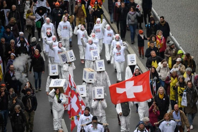 Protesters hold flags and banners during a protest against the current measures to tackle the spread of the coronavirus, Covid-19 health pass and vaccination, in Lausanne on November 20, 2021.