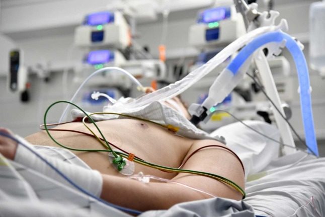 A person with tubes coming out of their body in an ICU. 
