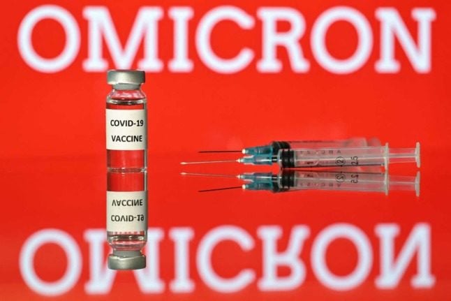 A close up of the Covid vaccine with the word Omicron in the background