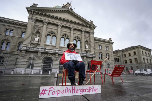 This file photo taken in Bern on November 28, 2021 shows Swiss Guillermo Fernandez holding a sign reading 