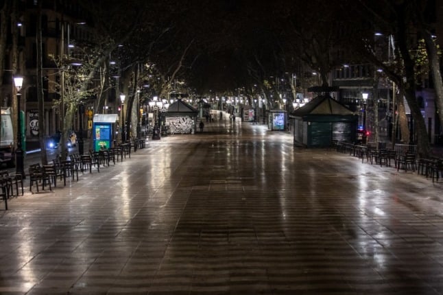 Few pedestrians walk in the empty central street of La Rambla, in Barcelona