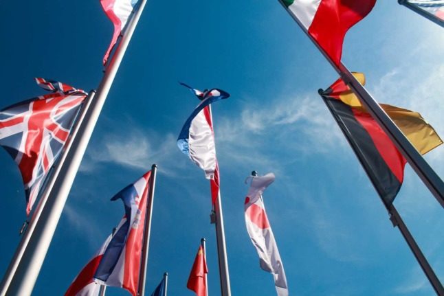 Flags from various nations against a blue sky