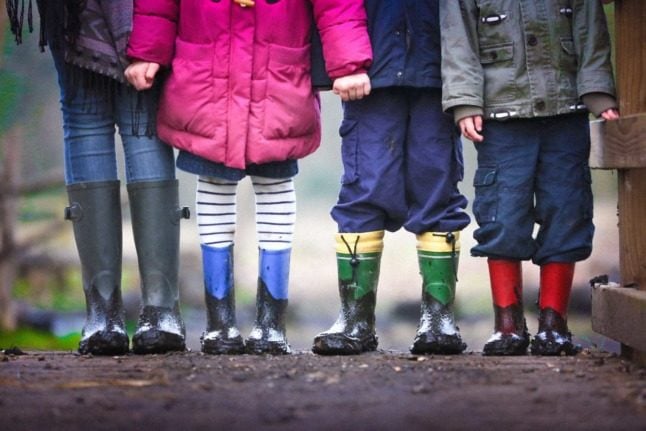 Children in gumboots line up next to each other on a muddy track